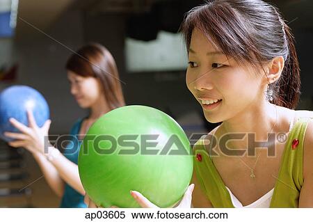 Stock Photography - Two women holding bowling balls, preparing to bowl . Fotosearch
