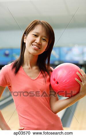 Woman at bowling alley holding bowling ball, hand on hip View Large Photo Image Stock Image - Woman at bowling alley holding bowling ball, hand on hip . Fotosearch