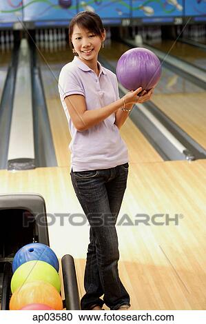 Woman at bowling alley holding bowling ball, smiling View Large Photo Image Stock Image - Woman at bowling alley holding bowling ball, smiling . Fotosearch