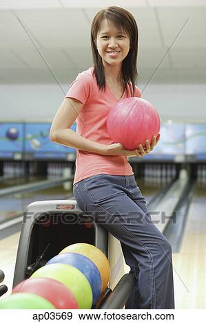 Stock Photo - Woman at bowling alley holding bowling ball . Fotosearch