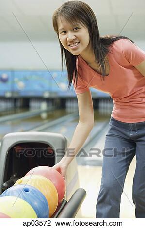 Woman at bowling alley selecting bowling ball, smiling at camera View Large Photo Image Stock Image - Woman at bowling alley selecting bowling ball, smiling at camera . Fotosearch