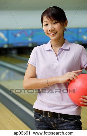 Woman at bowling alley, smiling, holding bowling ball under arm View Large Photo Image Stock Image - Woman at bowling alley, smiling, holding bowling ball under arm. Fotosearch