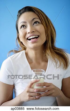 Stock Photography - Woman holding a glass of milk, looking up . Fotosearch