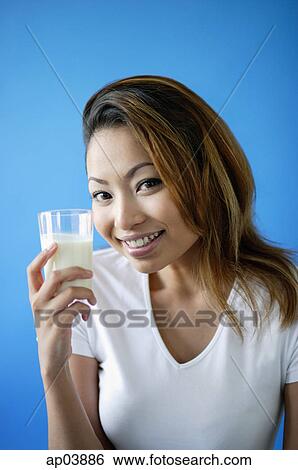 Woman holding a glass of milk, smiling at camera View Large Photo Image Stock Photograph - Woman holding a glass of milk, smiling at camera. Fotosearch