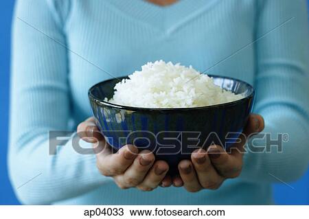 Stock Image - Woman holding bowl of rice, cropped image . Fotosearch