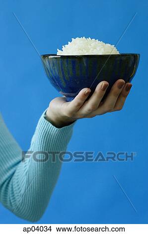 Woman holding bowl of rice in one hand View Large Photo Image Picture - Woman holding bowl of rice in one hand. Fotosearch