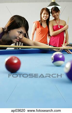 Woman holding pool cue, aiming, women watching in the background View Large Photo Image Stock Image - Woman holding pool cue, aiming, women watching in the background. Fotosearch
