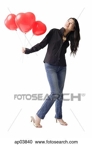 Stock Image - Woman holding three red balloons, looking up. Fotosearch