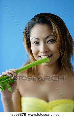 Woman looking at camera, eating celery View Large Photo Image Stock Photo - Woman looking at camera, eating celery. Fotosearch