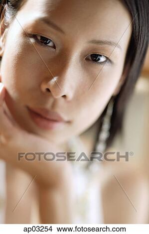 Picture - Woman looking at camera, hand on chin. Fotosearch