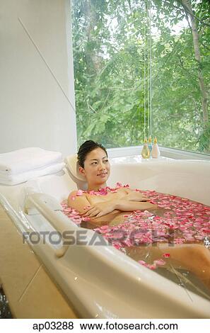 Woman lying in bath tub, flowers floating in water View Large Photo Image Stock Photo - Woman lying in bath tub, flowers floating in water. Fotosearch