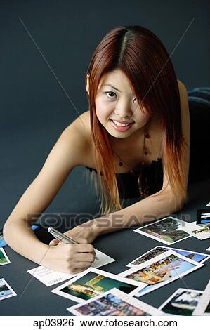 Woman lying on floor, writing on backs of postcards View Large Photo Image Stock Photograph - Woman lying on floor, writing on backs of postcards. Fotosearch