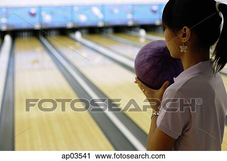 Stock Image - Woman preparing to bowl, over the shoulder view . Fotosearch