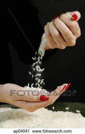 Stock Image - Woman sifting rice between fingers . Fotosearch