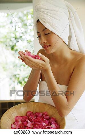 Stock Image - Woman smelling flower petals in cupped hands. Fotosearch