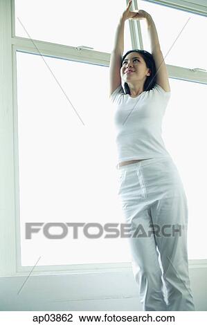 Stock Image - Woman standing and stretching arms . Fotosearch