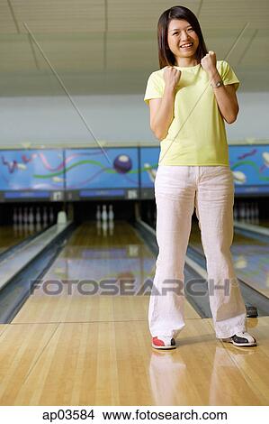 Woman standing at bowling alley, hands in fists, smiling View Large Photo Image Picture - Woman standing at bowling alley, hands in fists, smiling . Fotosearch