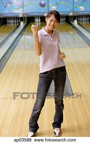 Woman standing at bowling alley, smiling, making a fist View Large Photo Image Stock Photo - Woman standing at bowling alley, smiling, making a fist. Fotosearch