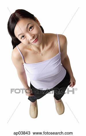 Stock Image - Woman standing, smiling at camera, high angle view. Fotosearch
