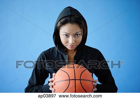 Woman wearing hooded shirt, holding basketball, looking at camera View Large Photo Image Stock Photo - Woman wearing hooded shirt, holding basketball, looking at camera . Fotosearch