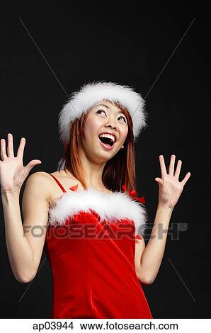 Picture - Woman wearing Santa hat and red dress, mouth open in surprise. Fotosearch