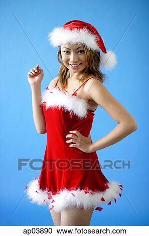 Stock Image - Woman wearing Santa hat and red dress, smiling at camera . Fotosearch