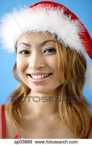 Stock Photo - Woman wearing Santa hat, smiling at camera . Fotosearch