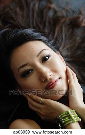 Stock Photo - Woman with hands on face, looking at camera. Fotosearch