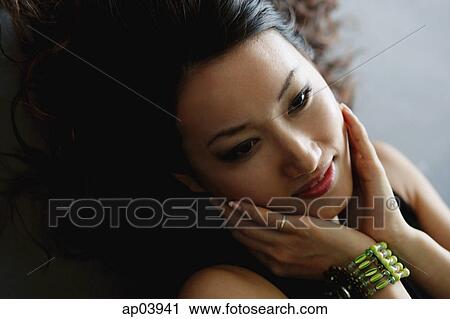 Stock Image - Woman with hands on face, looking away . Fotosearch