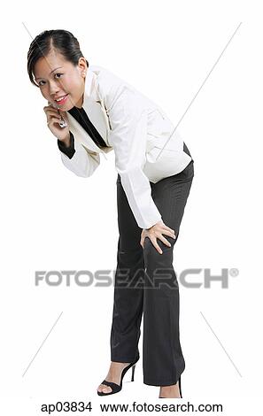 Picture - Woman with mobile phone, bending forward. Fotosearch