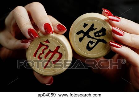 Stock Photo - Womans hands holding Chinese chess pieces. Fotosearch