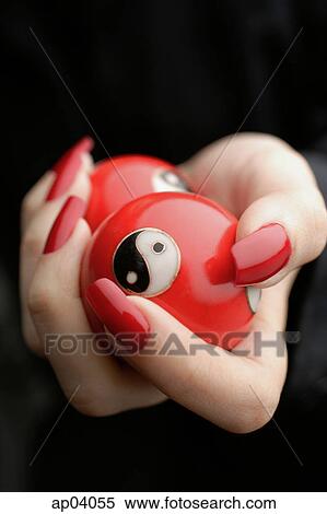 Stock Photography - Womans hands with red nail polish, holding Yin Yang balls, close-up . Fotosearch