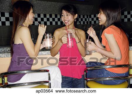 Women at bar counter, with drinks, talking to each other View Large Photo Image Picture - Women at bar counter, with drinks, talking to each other . Fotosearch