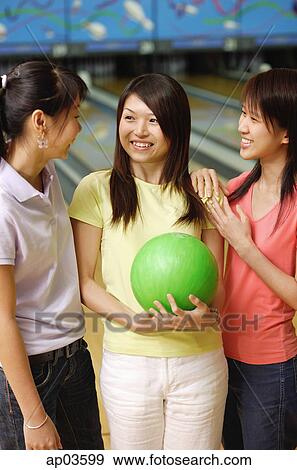 Stock Photo - Women at bowling alley, standing side by side. Fotosearch