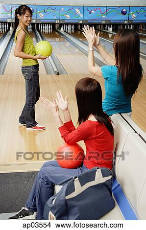 Women in bowling alley, cheering friend on View Large Photo Image Picture - Women in bowling alley, cheering friend on . Fotosearch
