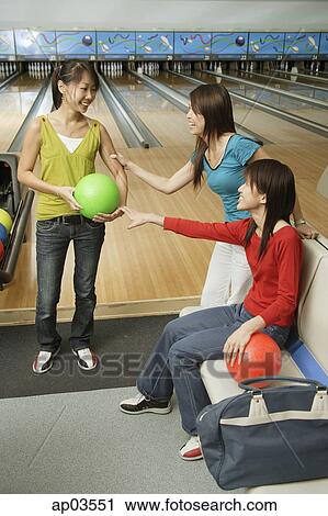 Stock Image - Women in bowling alley, one choosing ball . Fotosearch