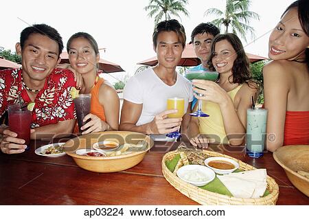 Picture - Young adults having drinks at beach bar . Fotosearch
