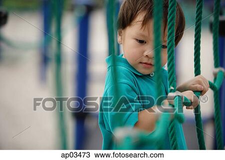 Young boy in playground, holding on to rope net View Large Photo Image Stock Image - Young boy in playground, holding on to rope net . Fotosearch