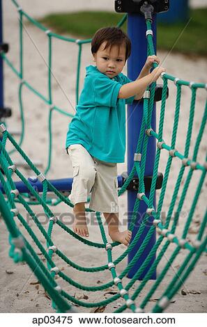 Young boy in playground, walking on net bridge View Large Photo Image Stock Photography - Young boy in playground, walking on net bridge . Fotosearch