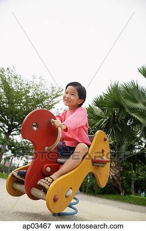 Young girl in playground, riding hobby horse View Large Photo Image Stock Photo - Young girl in playground, riding hobby horse . Fotosearch