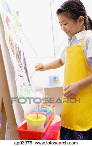 Young girl in yellow apron, painting on easel View Large Photo Image Stock Photograph - Young girl in yellow apron, painting on easel . Fotosearch