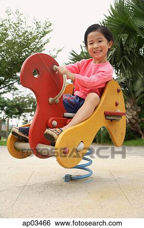 Young girl sitting on hobby horse in playground View Large Photo Image Stock Photograph - Young girl sitting on hobby horse in playground . Fotosearch