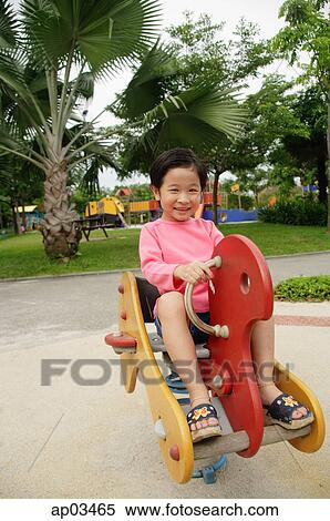 Young girl sitting on playground hobby horse View Large Photo Image Stock Photography - Young girl sitting on playground hobby horse . Fotosearch