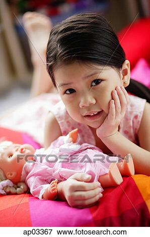 Young girl with doll, hand on chin, looking at camera View Large Photo Image Stock Photo - Young girl with doll, hand on chin, looking at camera . Fotosearch