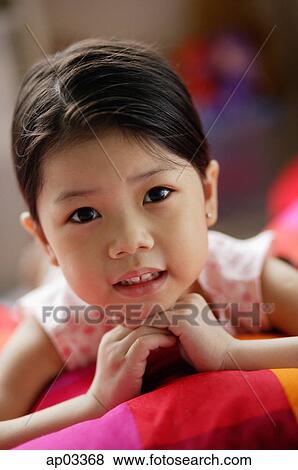 Stock Photo - Young girl with hands on chin, looking at camera . Fotosearch
