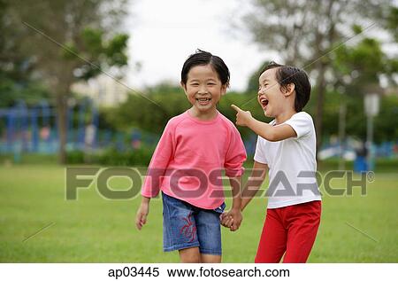 Stock Photography - Young girls holding hands in park, laughing. Fotosearch