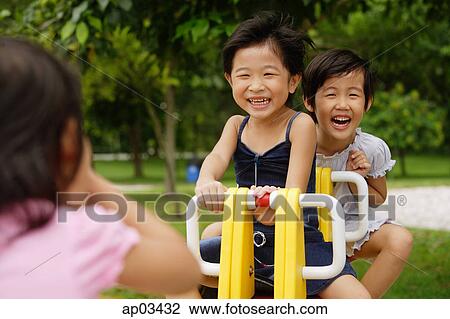 Young girls in playground, playing on seesaw View Large Photo Image Stock Image - Young girls in playground, playing on seesaw . Fotosearch