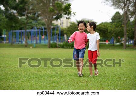 Picture - Young girls walking on grass, in park. Fotosearch