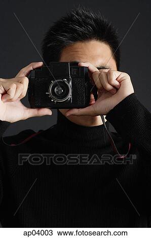 Young man dressed in black looking through camera View Large Photo Image Stock Image - Young man dressed in black looking through camera . Fotosearch