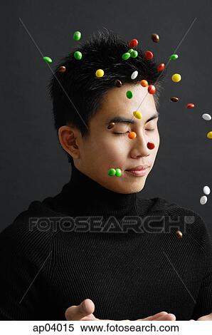 Young man dressed in black, throwing multi coloured candy in the air View Large Photo Image Stock Photography - Young man dressed in black, throwing multi coloured candy in the air . Fotosearch